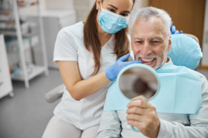 man smiling while looking at his implant overdentures